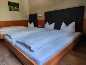 ein großes Bett mit weißer Bettwäsche und Kissen in der Unterkunft Gasthof Zahler in Röfingen