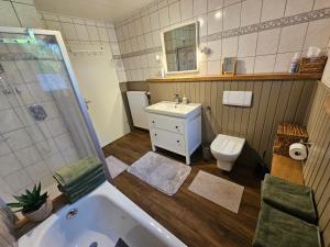 a bathroom with a tub and a sink and a toilet at Ferienhaus Fehntraum - Entdecke Ostfriesland in Großefehn  +17 photos