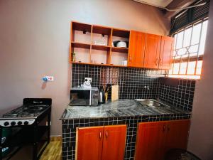 a kitchen with brown cabinets and a black tile counter top at The Urban Edge in Makerere