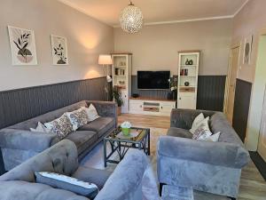 a living room with two couches and a tv at Ferienhaus Fehntraum - Entdecke Ostfriesland in Großefehn 