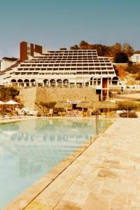 duży budynek z basenem przed nim w obiekcie Cala San Miguel Hotel Ibiza, Curio Collection by Hilton, Adults only w mieście Puerto de San Miguel