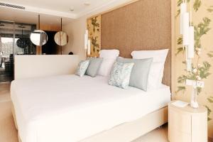 una camera da letto con un grande letto bianco con cuscini di Cala San Miguel Hotel Ibiza, Curio Collection by Hilton, Adults only a Puerto de San Miguel