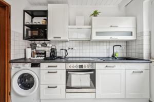 a kitchen with white cabinets and a washer and dryer at P&K Apartment in Dinslaken