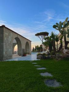 un bâtiment en briques avec une arche dans l'herbe dans l'établissement Resort Villa Flavio, à Ischia