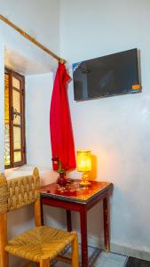 a table with a lamp and a red dress on a wall at Hotel imouzzer in Marrakech