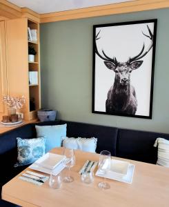 una mesa con copas de vino y una foto de un ciervo en Maria Alm - komfortables Apartment Gipfelglück en Saalfelden am Steinernen Meer