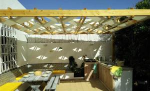 d'une terrasse avec une table et une pergola en bois. dans l'établissement Dar Gitta & Wood El Haouaria, à El Haouaria