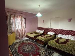 Habitación con 3 camas y espejo. en Hotel Tanout en Azilal