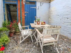 une table en bois avec deux chaises et une porte bleue dans l'établissement 26 High West, à Weymouth