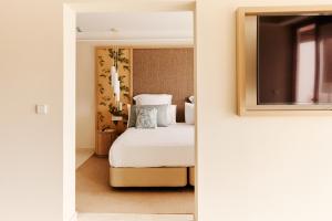 sypialnia z białym łóżkiem i lustrem w obiekcie Cala San Miguel Hotel Ibiza, Curio Collection by Hilton, Adults only w mieście Puerto de San Miguel