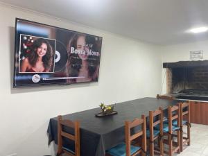 a dining room with a black table with chairs and a tv at El Descanso Casa de retiro in Tandil