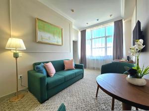 uma sala de estar com um sofá verde e uma mesa em Maestro Address Hotel em Baku