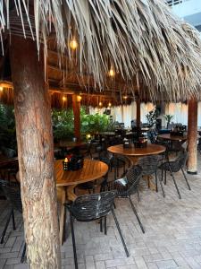 a restaurant with wooden tables and chairs and a straw umbrella at Ocean Manor Tiki Sunset Retreat in Fort Lauderdale