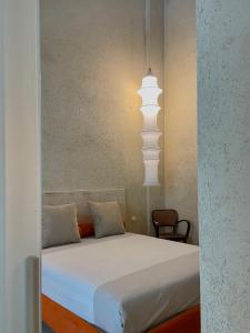 a bedroom with a bed with white sheets and a lamp at FUTURA ROOM&RELAX in Termoli