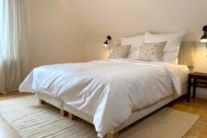 een slaapkamer met een wit bed met witte lakens en kussens bij Das Winzereck - 4 Sterne Ferienhaus in der Südpfalz in Ranschbach +35 foto's
