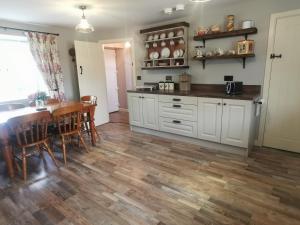 a kitchen with white cabinets and a table and chairs at Christie's Cottage in Dungiven