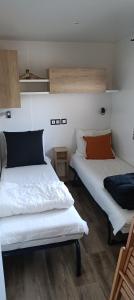 2 bedden in een kamer met witte lakens en oranje kussens bij Chalet Cozy Cove te Lauwersoog in Lauwersoog
