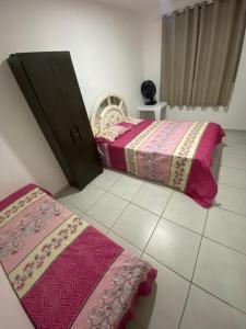 Duas camas num quarto com lençóis cor-de-rosa em Condomínio encantador em Caruaru