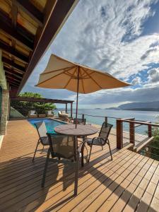 uma mesa e cadeiras com um guarda-sol num deque em Bela casa c/ vista privilegiada, à 1km da Ilha das Cabras em Ilhabela