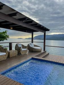 uma piscina com cadeiras e vista para a água em Bela casa c/ vista privilegiada, à 1km da Ilha das Cabras em Ilhabela
