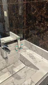 La salle de bains blanche est pourvue d'un lavabo et d'un miroir. dans l'établissement بلند للشقق المخدومة, à Dammam