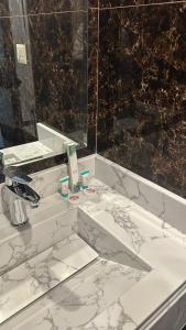 a white bathroom with a sink and a mirror at بلند للشقق المخدومة اقتصادي in Dammam