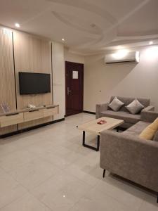 a living room with a couch and a tv at بلند للشقق المخدومة اقتصادي in Dammam