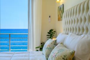 a bedroom with a white bed with a large window at Perla Apartments in Agios Nikolaos