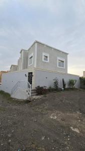 ein großes weißes Haus mit einer Treppe davor in der Unterkunft دور فخم ومتكامل بالقرب من عسير مول in ‘Aryam