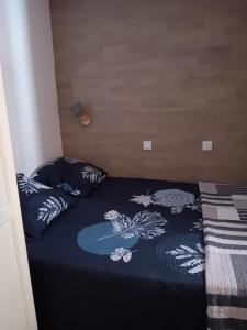 a bed with a blue comforter and two pillows at Appartement T2 avec piscine a 100 m de la plage in Six-Fours-les-Plages