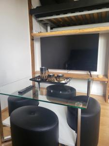 TV y mesa de cristal con sillas negras. en Le studio, en Bonzac