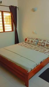 Una cama sentada en una habitación con ventana. en Riche ag, en Cotonou