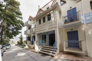 a white house with blue shutters on a street at FoRest & sea view apartment in Argostoli