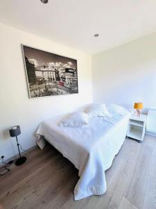 une chambre blanche avec un lit et un tableau sur le mur dans l'établissement Studio, piscine, parking, à Saint-Tropez 1 autre photo