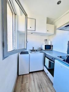 une cuisine blanche avec un évier et une fenêtre dans l'établissement Studio, piscine, parking, à Saint-Tropez