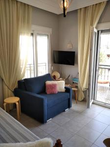 a living room with a blue couch and a tv at ISLAND VIEW BEACH APARTMENT in Néa Péramos