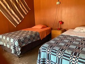 1 dormitorio con 2 camas y mesita de noche con lámpara en Paracas Camp Lodge & Experiences, en Paracas