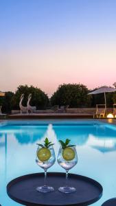 two wine glasses with lemons in them on a table by a pool at Fiore di Vendicari B&B - Sicilian Charme, Lemon Grove and Sea in Noto