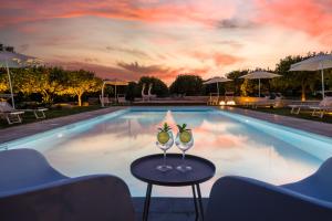 a pool with two wine glasses on a table next to it at Fiore di Vendicari B&B - Sicilian Charme, Lemon Grove and Sea in Noto