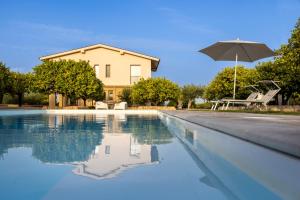 una piscina con sombrilla y una casa en Fiore di Vendicari - Near the beaches of Calamosche and Vendicari en Noto