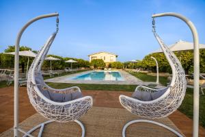 a pair of hanging chairs in front of a pool at Fiore di Vendicari B&B - Sicilian Charme, Lemon Grove and Sea in Noto