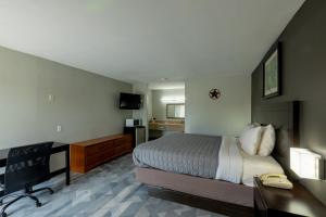 a hotel room with a bed and a desk and a television at Freer Executive Inn & Studios in Freer