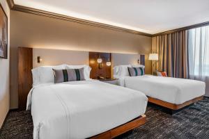 2 camas en una habitación de hotel con sábanas blancas en Omni Austin Hotel Downtown, en Austin