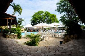 um pátio com mesas e guarda-sóis e uma piscina em Amoaras Resort em Maria Farinha