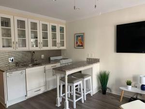 a kitchen with white cabinets and a tv on the wall at Shore To Please! Elegant couples retreat with bikes in Hilton Head Island