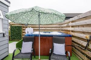 a patio table with two chairs and an umbrella at Adorable private couples retreat with hot tub in Llanfechell