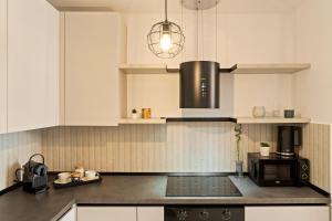 kuchnia z białymi szafkami i czarną kuchenką mikrofalową w obiekcie Rin Luxury Apartments Pool & Spa w Bukareszcie