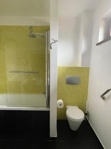 een badkamer met een douche, een toilet en gele tegels bij 2 ROOMS with bath in this nice house, POOL, seaview in Palafolls