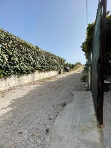 an empty road next to a wall with a hedge at Climbing House Chèrie Madeleine in Lido Di Fondi