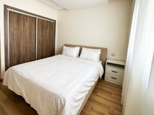een slaapkamer met een groot wit bed en een raam bij Appartement de luxe au Parc au centre pres de la plage in Mohammedia